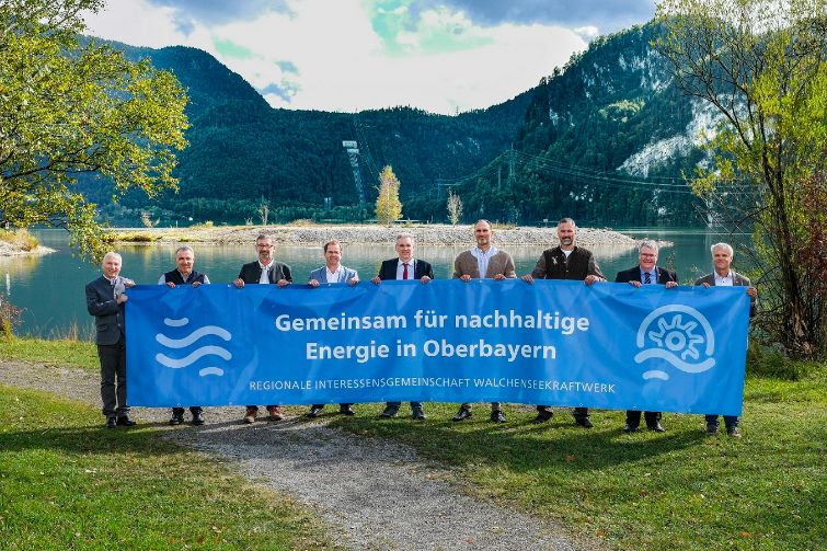 Regionalen Interessensgemeinschaft Walchenseekraftwerk. Die 9 teilnehmenden Personen halten ein blaues Banner