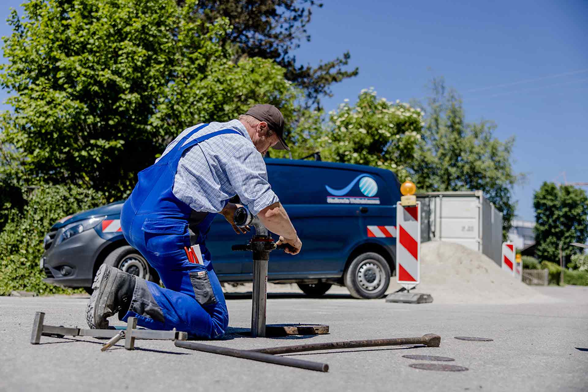 Mitarbeiter der Stadtwerke installiert eine Wasserleitung in einem Wasseranschluss auf der Straße